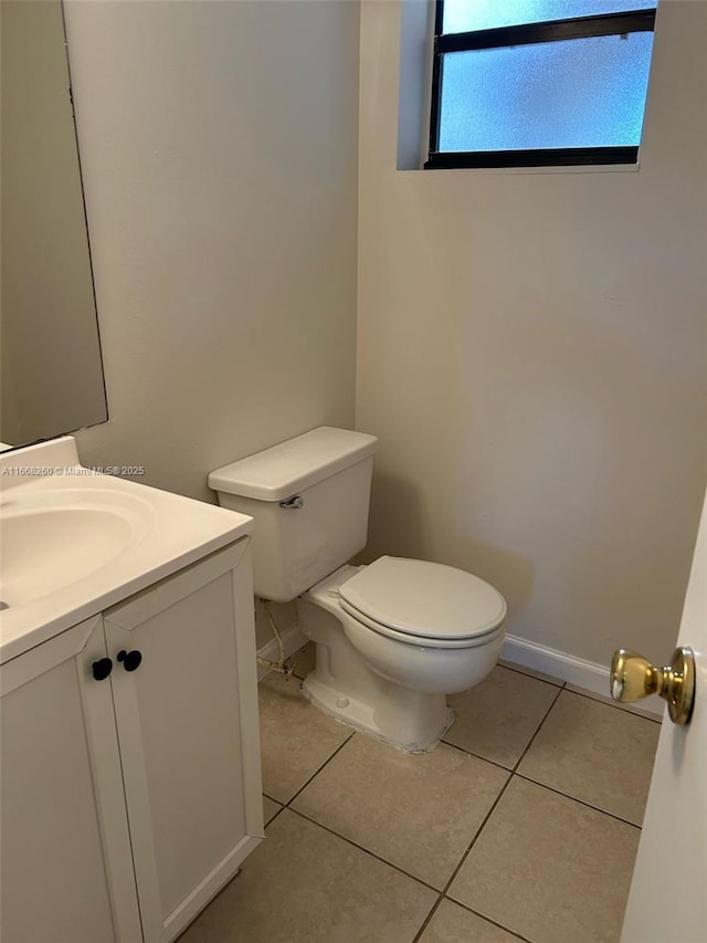 half bathroom with tile patterned floors, toilet, vanity, and baseboards