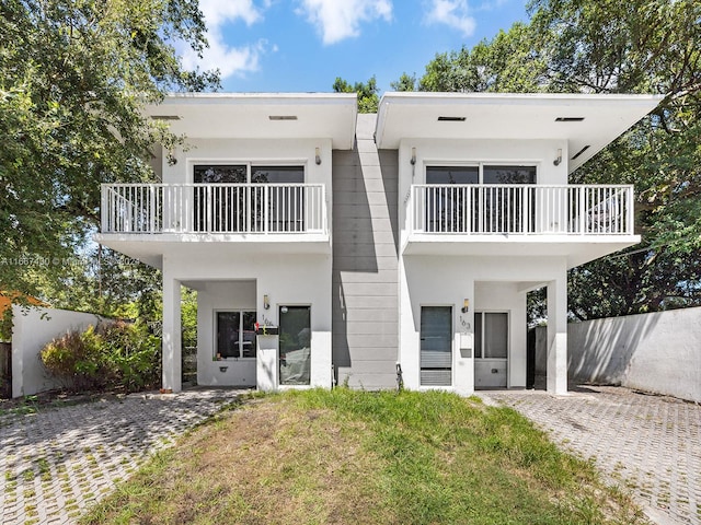 view of front of home with a balcony and a front lawn