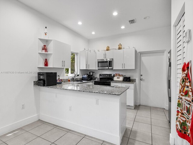 163 NW 68th Ter, Miami, FL 33150 - kitchen featuring stainless steel microwave, black / electric stove, open shelves, a peninsula, and white cabinetry