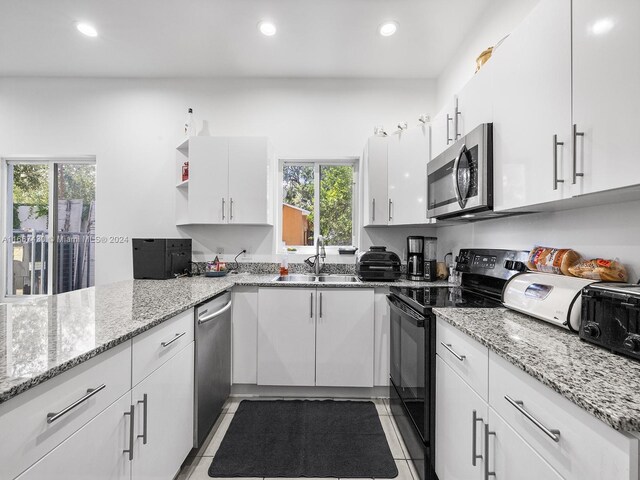 163 NW 68th Ter, Miami, FL 33150 - kitchen featuring stainless steel appliances, a sink, white cabinetry, light tile patterned flooring, and recessed lighting