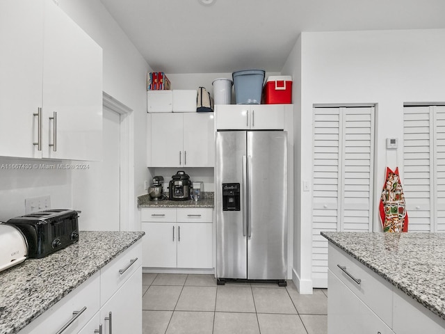 kitchen with white cabinets, stainless steel refrigerator with ice dispenser, light stone counters, and light tile patterned floors