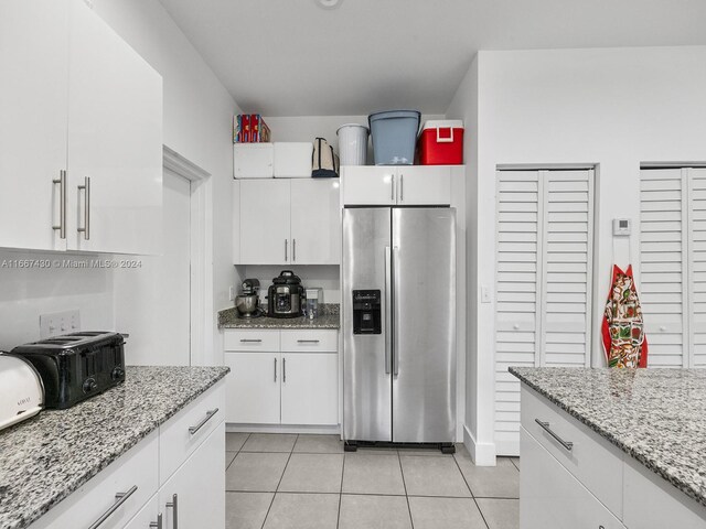 163 NW 68th Ter, Miami, FL 33150 - kitchen with stainless steel refrigerator with ice dispenser, light tile patterned flooring, white cabinetry, and light stone counters