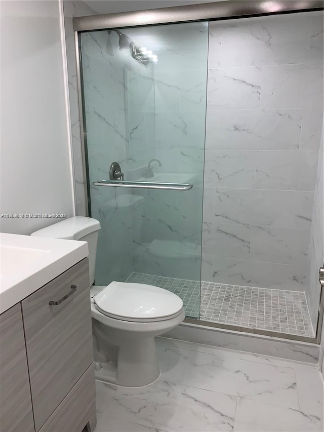 bathroom featuring a shower with door, vanity, and toilet