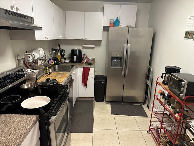 kitchen with stainless steel appliances, white cabinetry, light tile patterned flooring, and sink