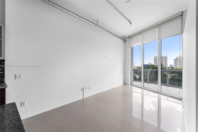 tiled spare room with a wall of windows