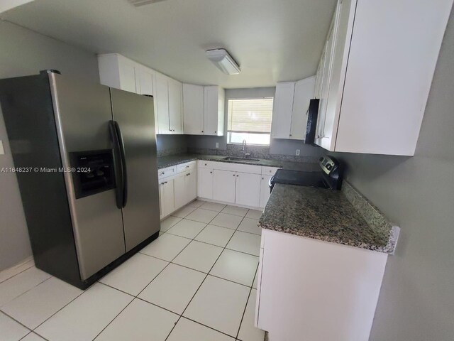 kitchen featuring sink, white cabinets, stainless steel fridge, dark stone counters, and range