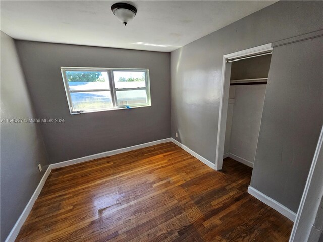 unfurnished bedroom with dark hardwood / wood-style floors and a closet