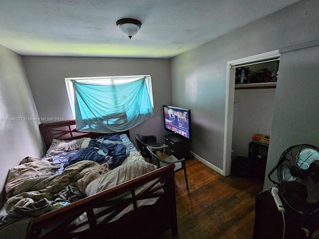 bedroom with dark hardwood / wood-style flooring and a closet