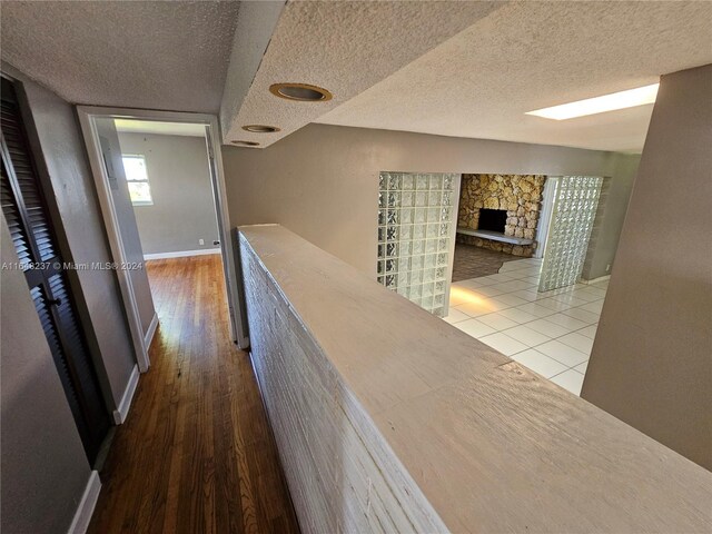 corridor with wood-type flooring and a textured ceiling