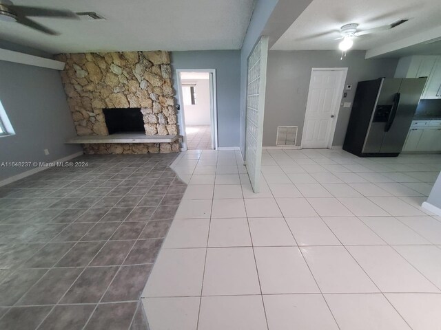 unfurnished living room with ceiling fan, light tile patterned floors, and a fireplace