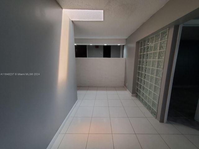 hall featuring light tile patterned floors and a textured ceiling