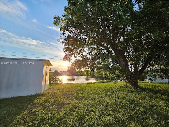 yard at dusk featuring a water view