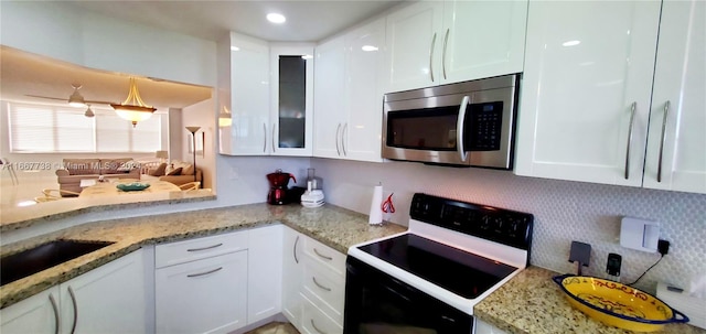 kitchen featuring white cabinets, light stone counters, and electric range