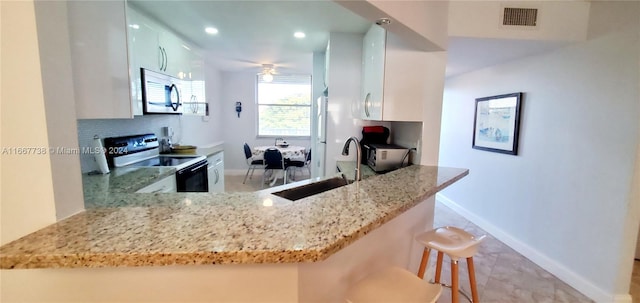 kitchen with sink, white cabinetry, kitchen peninsula, a kitchen bar, and stainless steel appliances