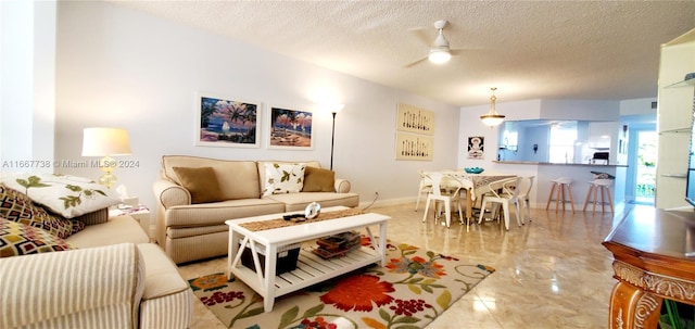 living room with ceiling fan and a textured ceiling