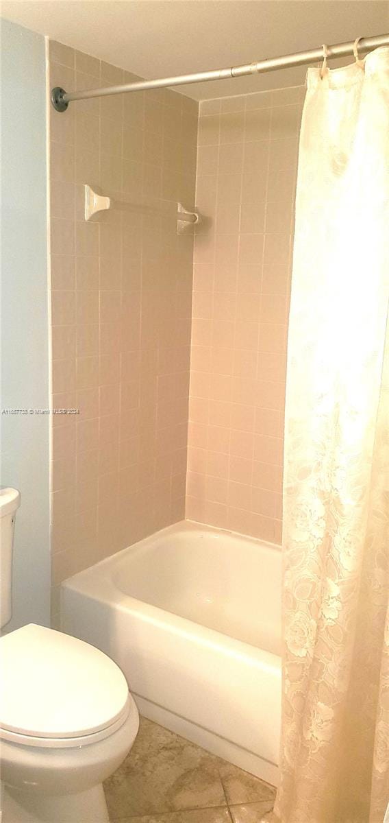 bathroom with shower / tub combo with curtain, tile patterned floors, and toilet