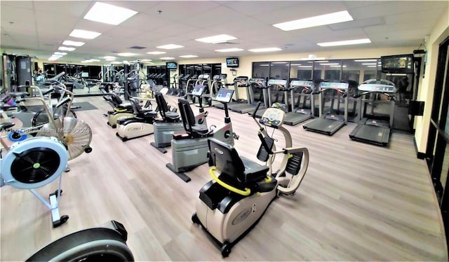 workout area with a paneled ceiling and light hardwood / wood-style floors