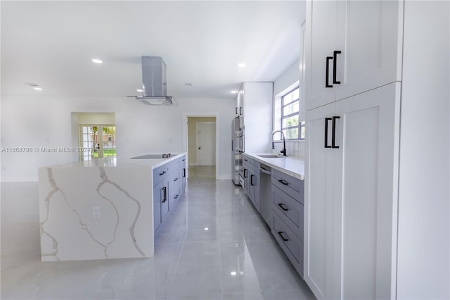 kitchen with white cabinets, sink, wall chimney exhaust hood, appliances with stainless steel finishes, and light stone countertops