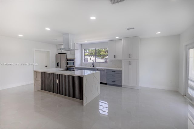 kitchen with tasteful backsplash, white cabinets, island range hood, a kitchen island, and stainless steel appliances