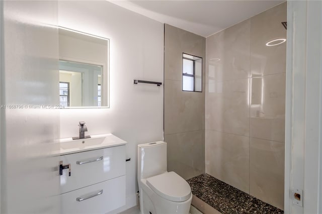 bathroom featuring a tile shower, vanity, and toilet