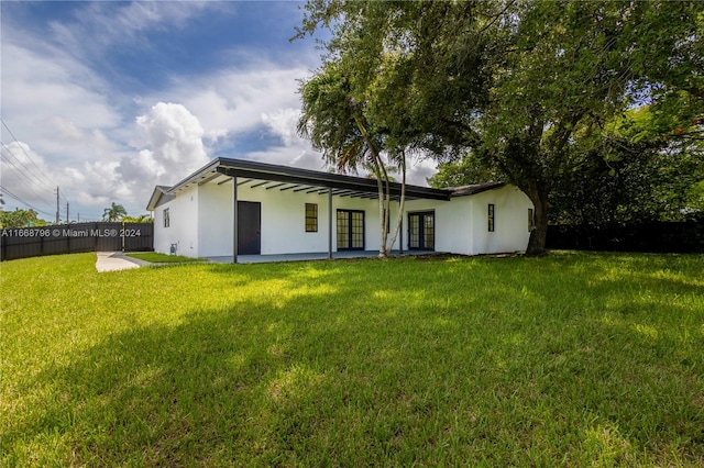 back of property featuring a lawn and ceiling fan