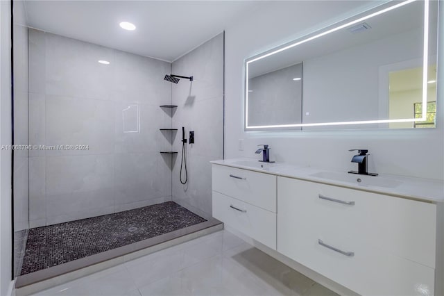 bathroom featuring tiled shower, vanity, and tile patterned flooring