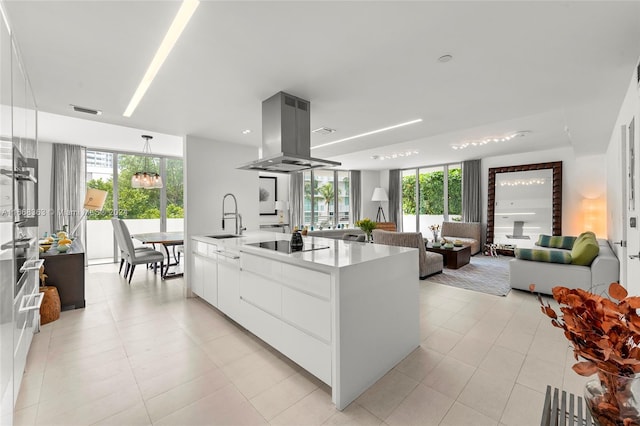 kitchen with white cabinets, sink, island exhaust hood, black electric cooktop, and a center island