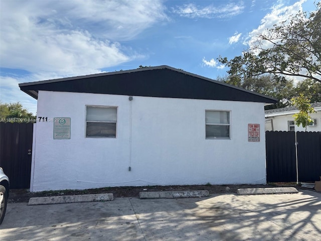 view of side of property with fence and stucco siding