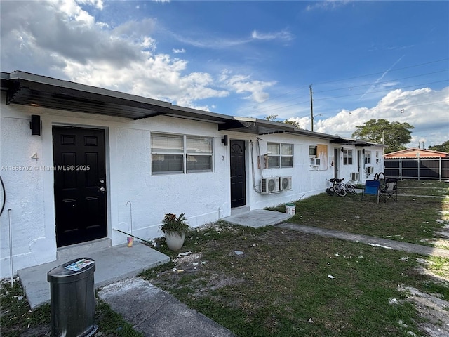 view of front facade featuring fence, a front lawn, and stucco siding