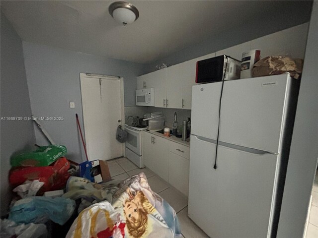711 SW 10th St, Dania Beach, FL 33004 - kitchen with white cabinetry, light tile patterned floors, light countertops, and white appliances