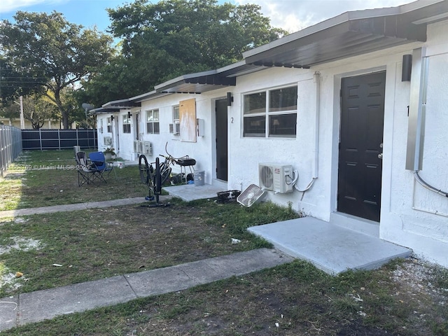 exterior space with ac unit, a front yard, fence, and stucco siding