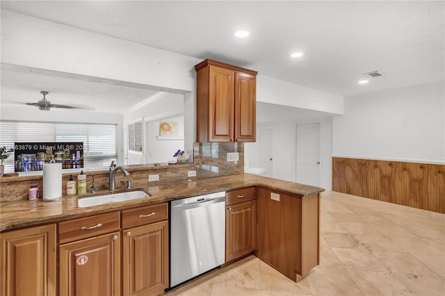 kitchen with ceiling fan, dishwasher, sink, light stone counters, and kitchen peninsula