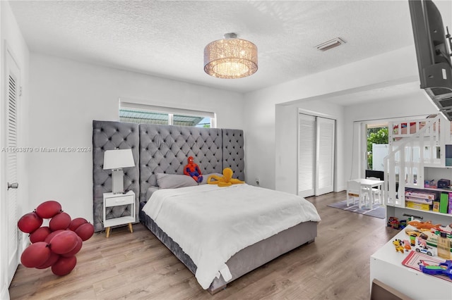 bedroom with wood-type flooring, a textured ceiling, and a closet