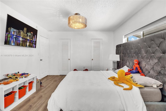 bedroom featuring wood-type flooring, a textured ceiling, and two closets