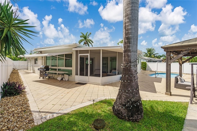 back of house featuring a sunroom, a fenced in pool, and a patio