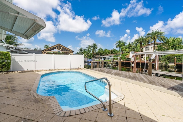 view of swimming pool with a boat dock, a water view, and a patio area