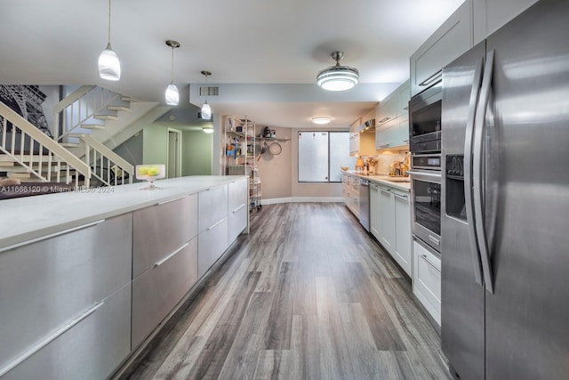 kitchen featuring light stone counters, decorative light fixtures, white cabinetry, appliances with stainless steel finishes, and dark hardwood / wood-style flooring