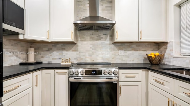 kitchen with tasteful backsplash, white cabinets, wall chimney exhaust hood, and stainless steel appliances