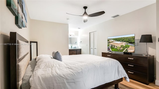 bedroom featuring light wood-type flooring, ceiling fan, and connected bathroom