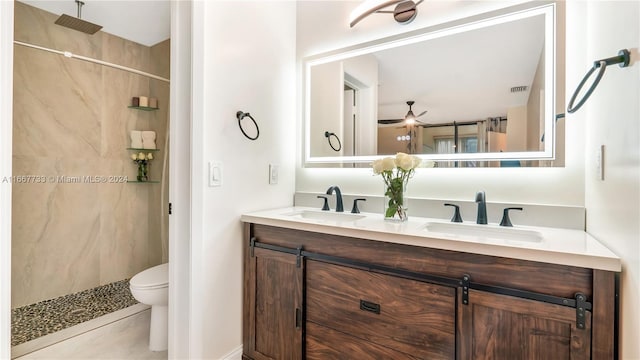 bathroom featuring vanity, tile patterned flooring, ceiling fan, toilet, and tiled shower