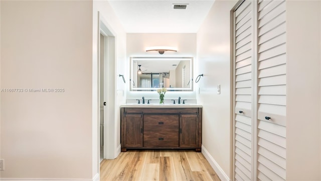 full bath featuring double vanity, baseboards, visible vents, wood finished floors, and a closet