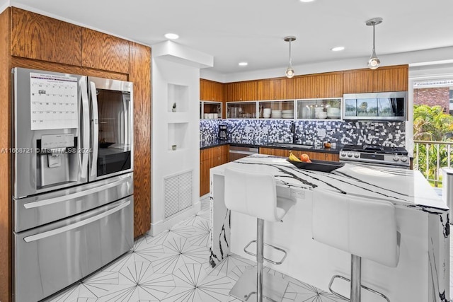 kitchen featuring hanging light fixtures, decorative backsplash, a breakfast bar area, stainless steel appliances, and sink