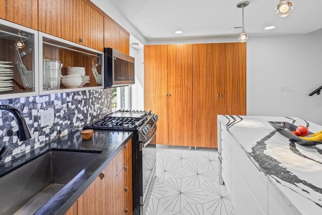 kitchen with decorative backsplash, stainless steel appliances, dark stone counters, and sink