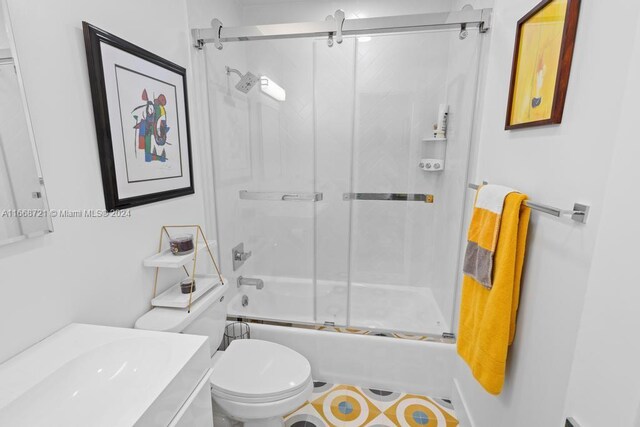 full bathroom with combined bath / shower with glass door, vanity, and toilet