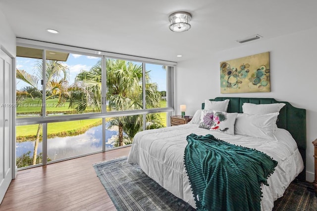 bedroom with floor to ceiling windows, multiple windows, and hardwood / wood-style floors