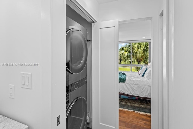 clothes washing area featuring stacked washer and dryer and hardwood / wood-style floors