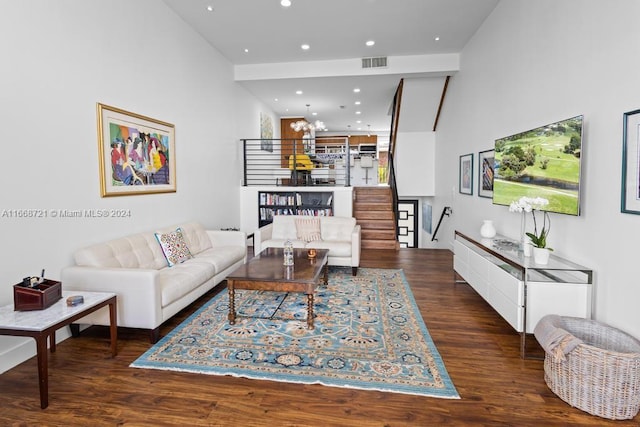 living room with a towering ceiling, an inviting chandelier, and dark hardwood / wood-style floors