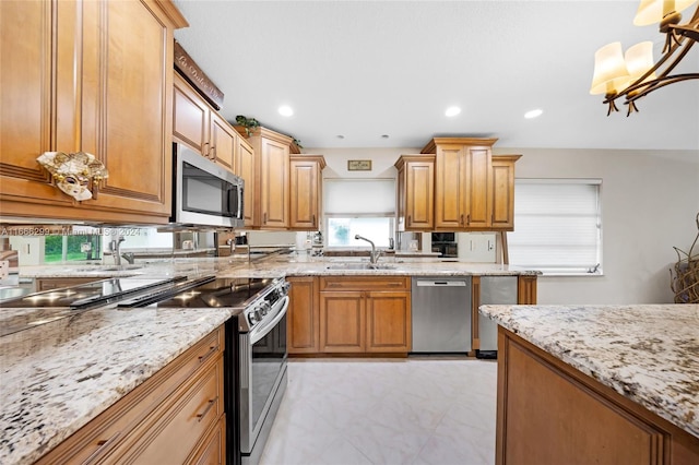 kitchen with hanging light fixtures, sink, appliances with stainless steel finishes, a notable chandelier, and light stone counters