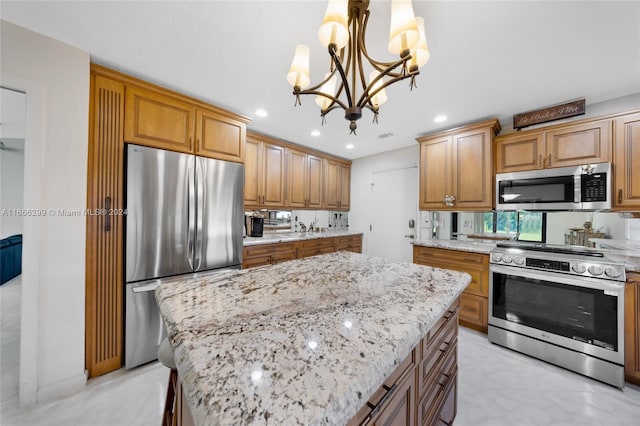 kitchen featuring light stone countertops, decorative light fixtures, a kitchen island, stainless steel appliances, and a chandelier