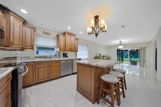 kitchen featuring appliances with stainless steel finishes, a breakfast bar, a notable chandelier, a kitchen island, and hanging light fixtures